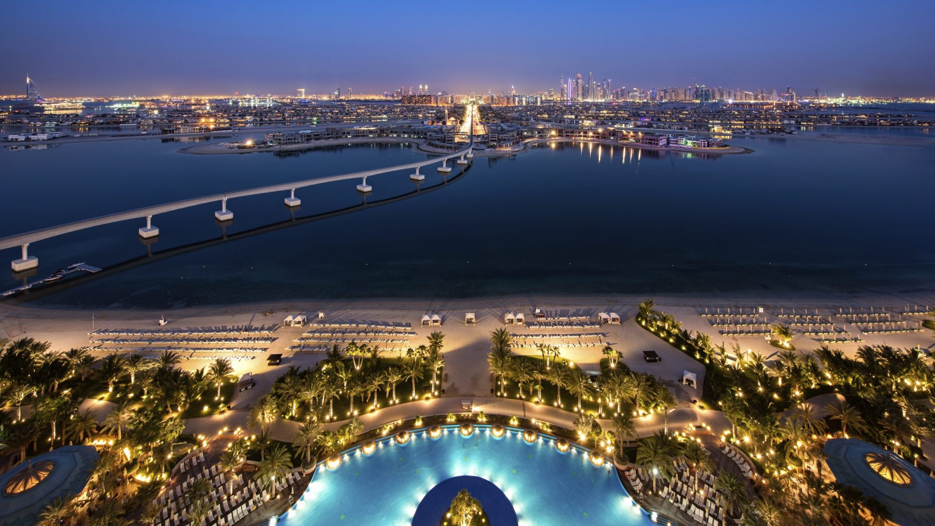 Cityscape of Dubai, United Arab Emirates at dusk, with bridge from  island across the Persian Gulf in the foreground.