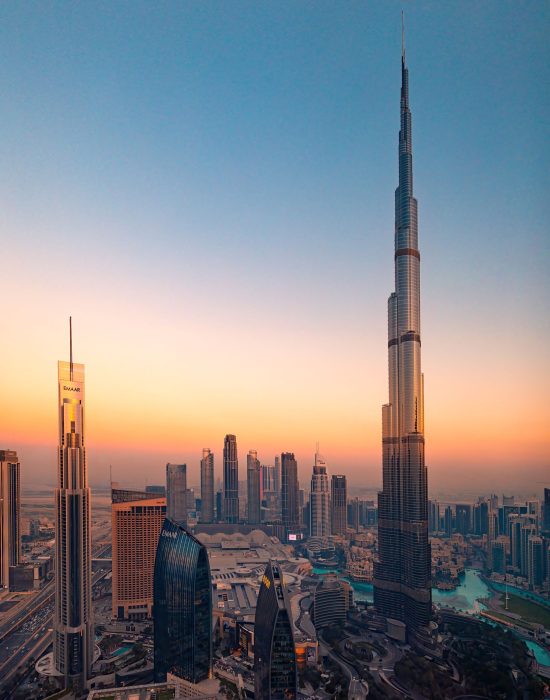 Aerial view of Burj Khalifa and Dubai skyline at sunset, showcasing modern skyscrapers and vibrant cityscape.