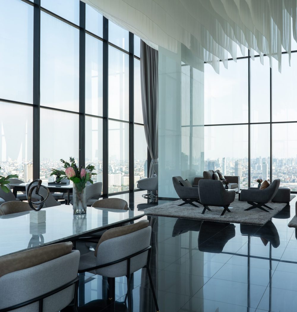 Interior of light living room with brown, grey sofas, coffee table and large window