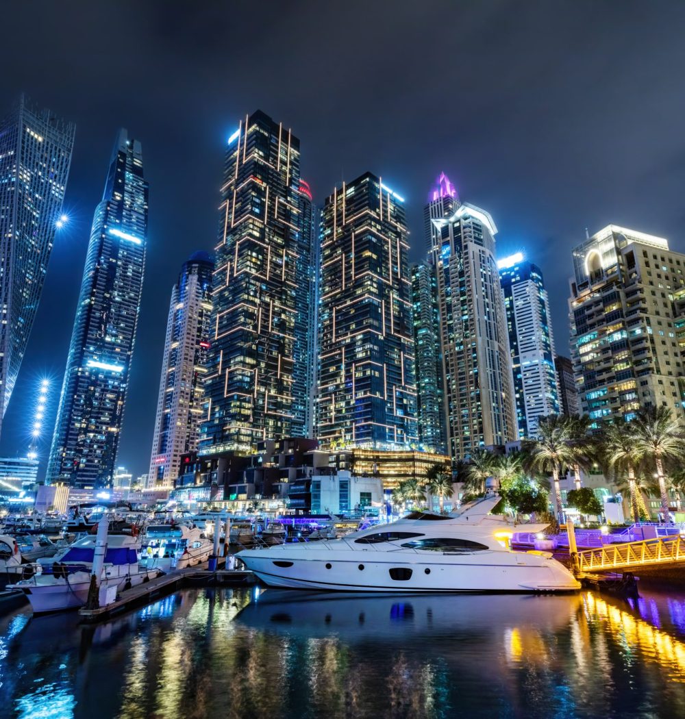 Marina with yachts and skyscrapers in Dubai UAE at night. United Arab Emirates